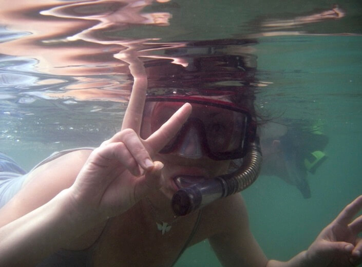 Snorkeling A young woman snorkels. She is seen from underwater and turns toward the lens with a "Peace sign."