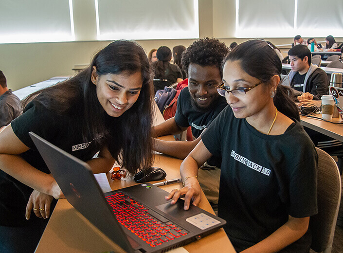 three students looking at computer