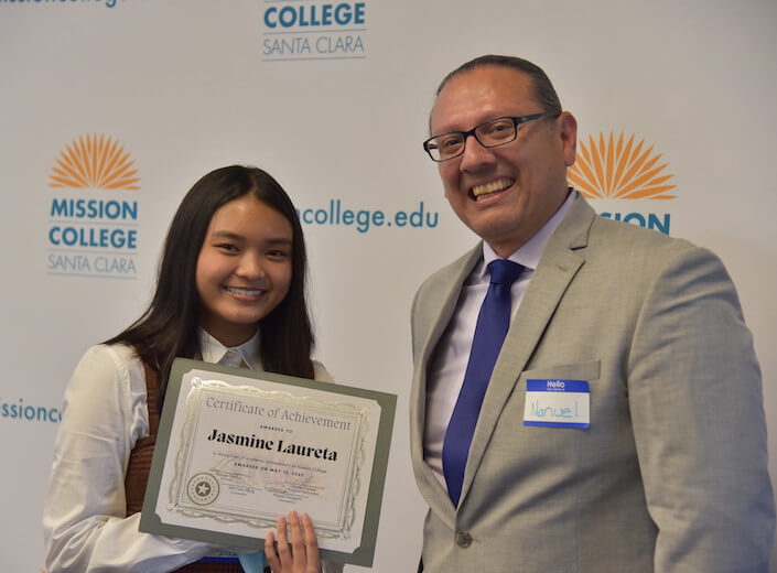 Manuel and student at TRIO ceremony. Manuel Salazar, a faculty member with glasses wearing a tan suit and a female TRIO student holding a certificate.